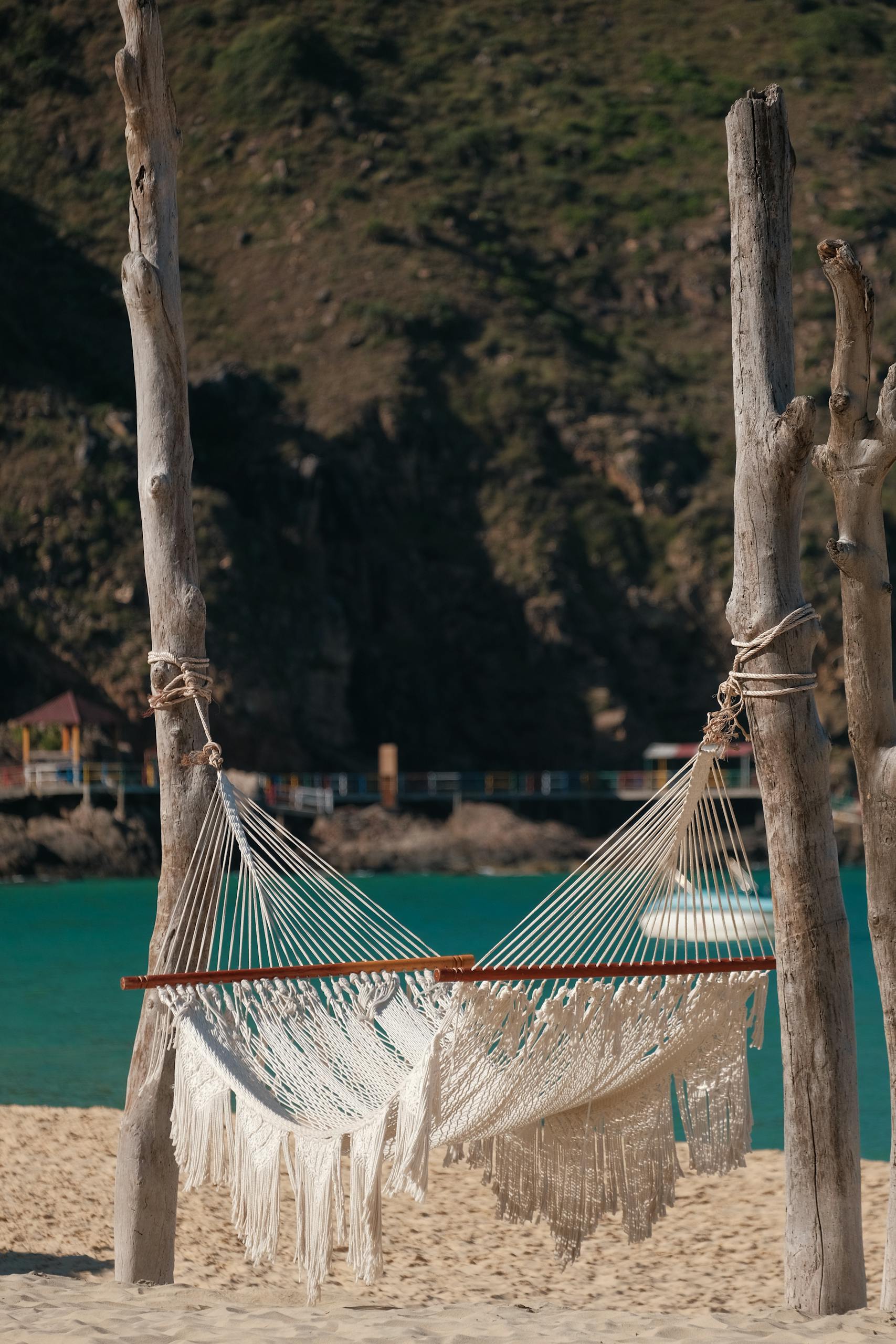 A peaceful hammock hanging on a sandy beach with a scenic ocean view.