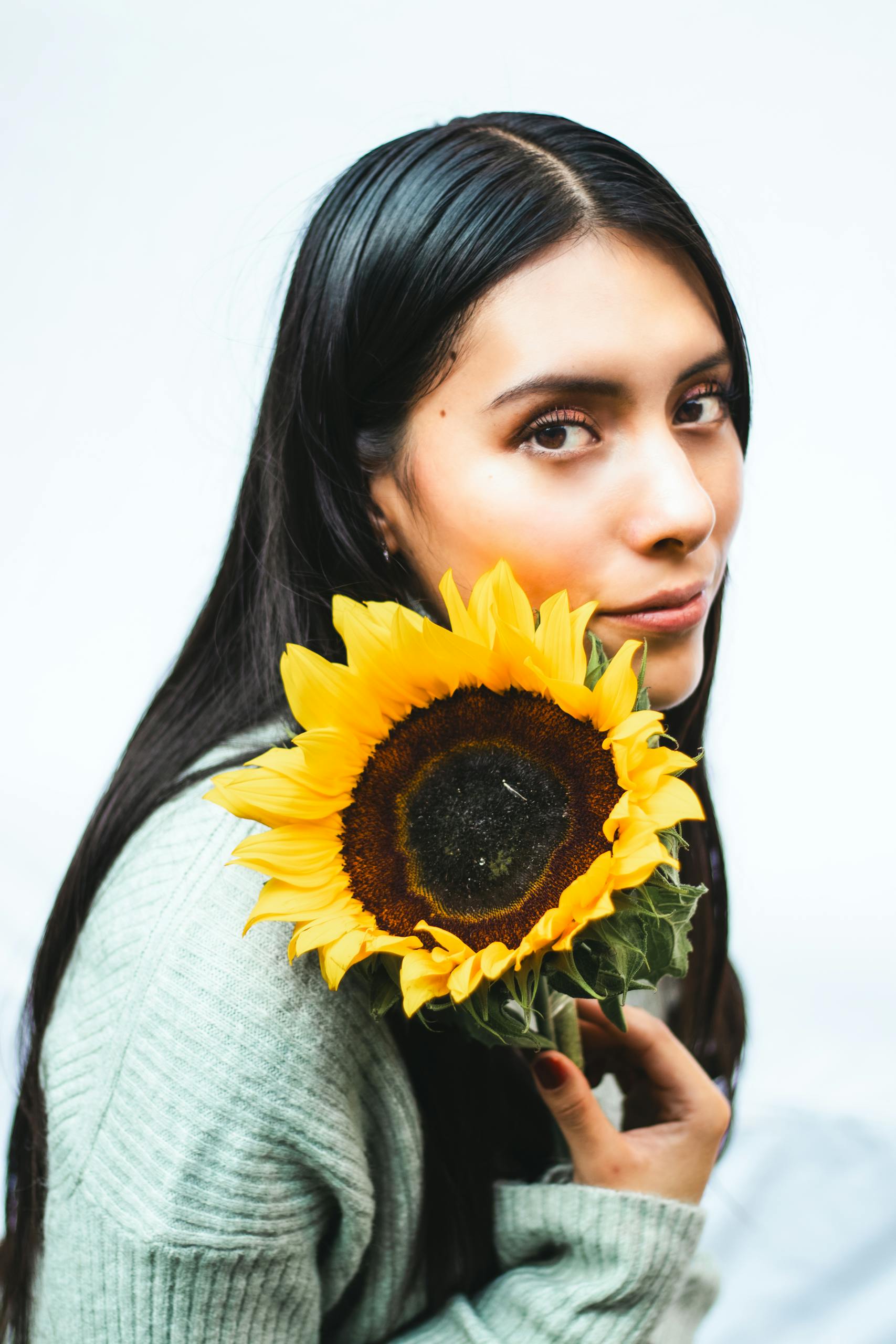 A serene portrait of a woman holding a vibrant sunflower, exuding summer warmth.
