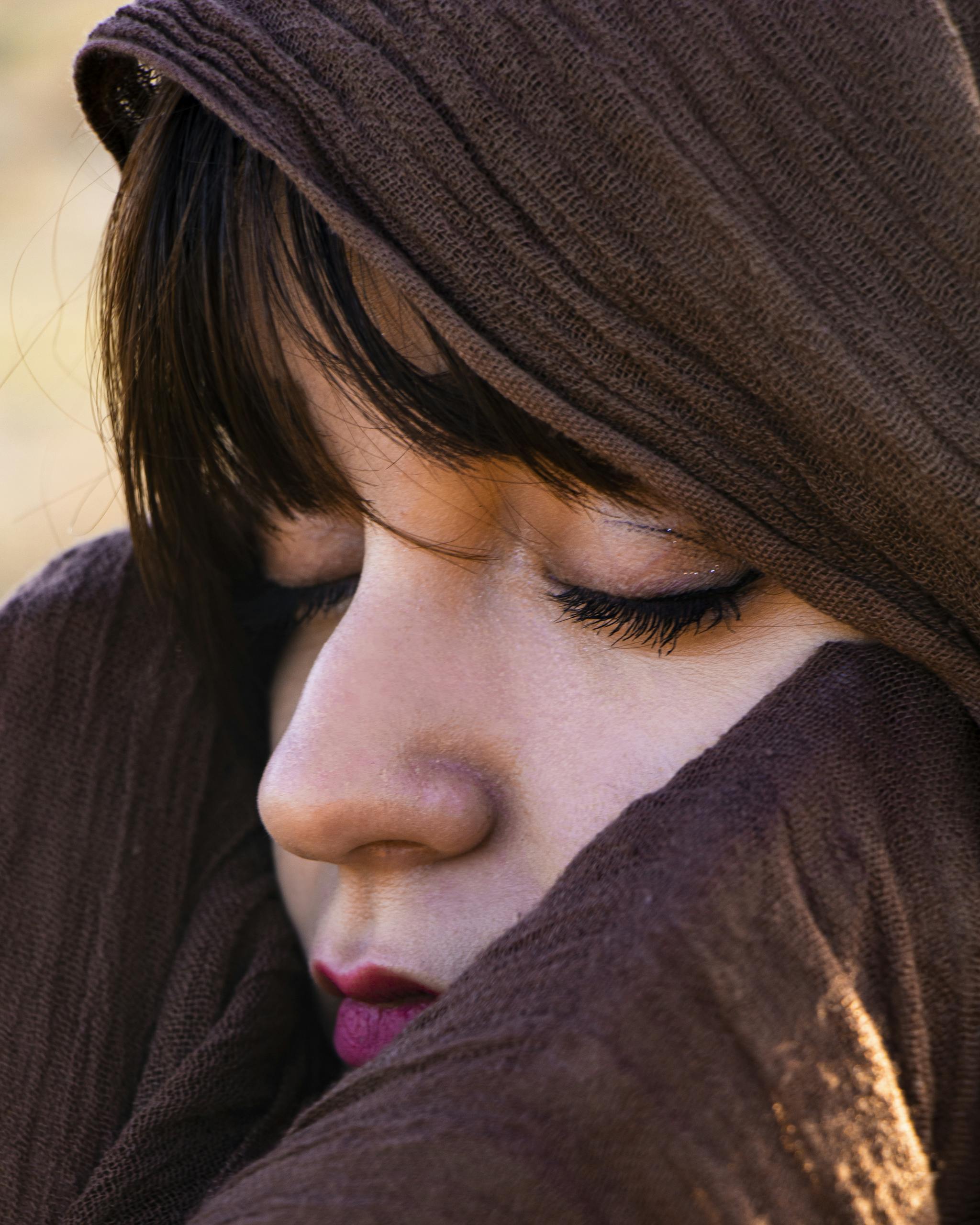Close-up portrait of a woman with eyes closed, wearing a hijab, evoking peace and serenity.